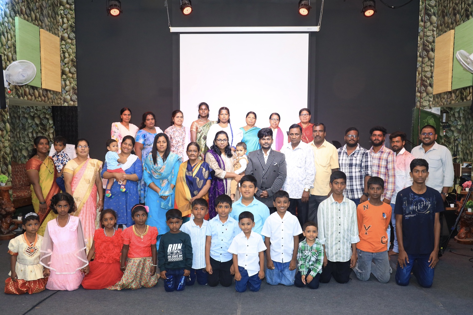 Christ Alive Church family gathered together in the church, with children in front and adults behind them.